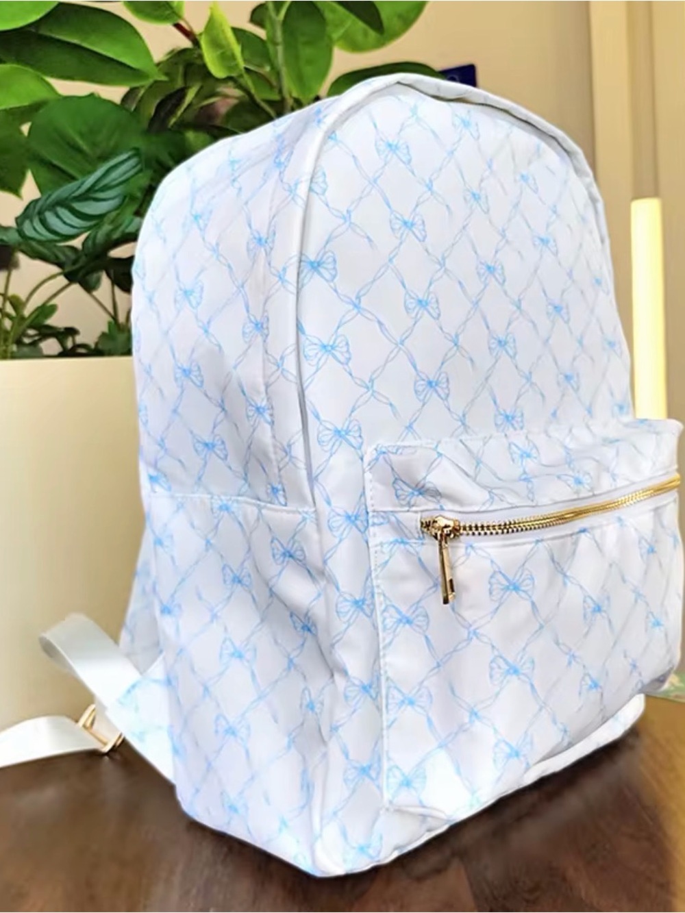 White Backpack with Light Blue Bow Pattern and Gold Zipper